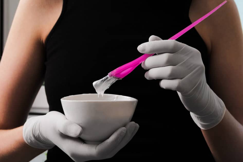 a woman wearing gloves and holding Hair Dye coloring brush