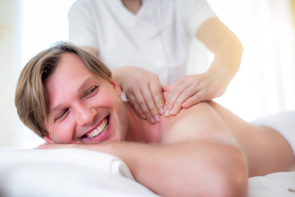 Man receiving a body massage from a Thai masseuse in a spa. 
