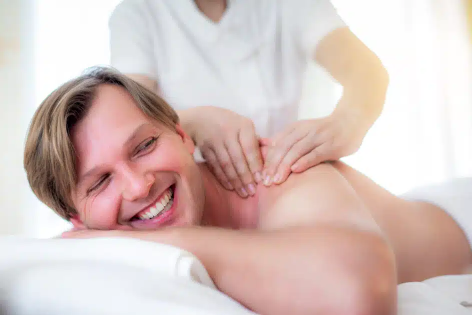 Man receiving a body massage from a Thai masseuse in a spa. 