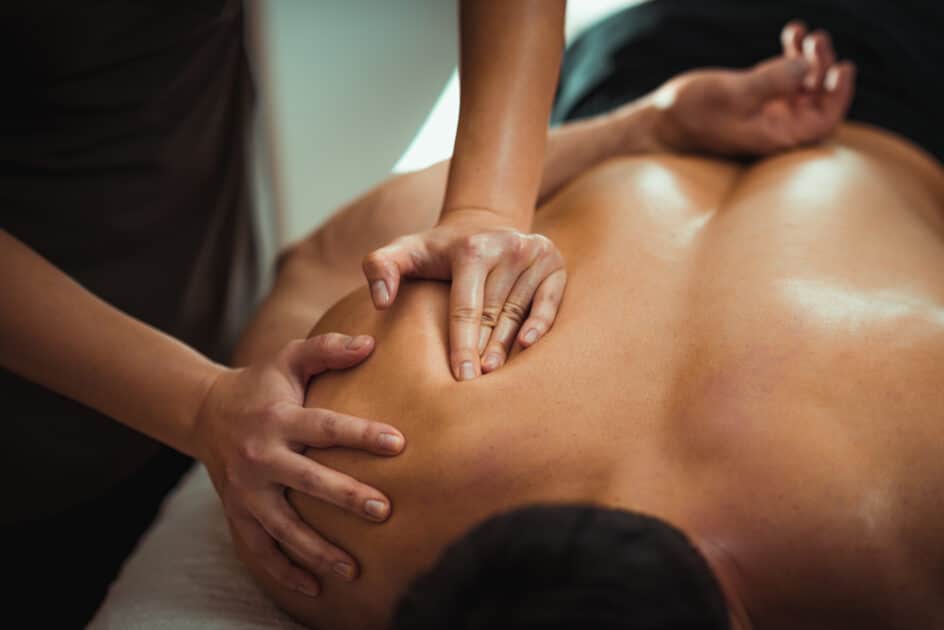 massaging male patient with damaged Fibromyalgia blade muscle. Treatment for sports injuries.