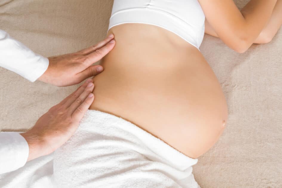 Man massaging a pregnant woman with his hands using Prenatal Massage
