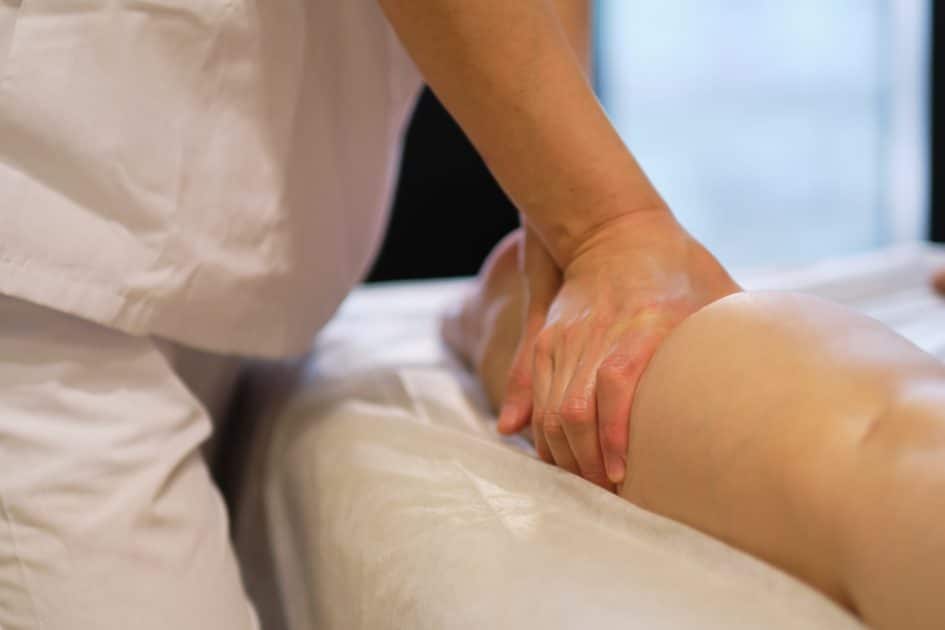 Young woman's legs being massaged by a massage therapist at a spa. 
