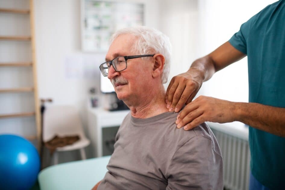 a  physiotherapist massages the neck of an elderly patient.