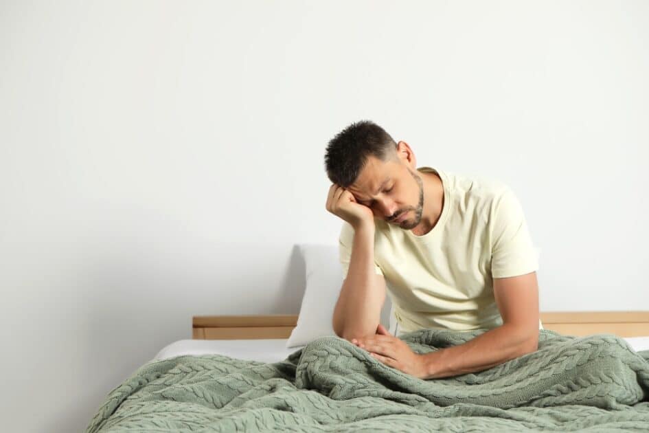 a picture of a tired man sitting in the bed