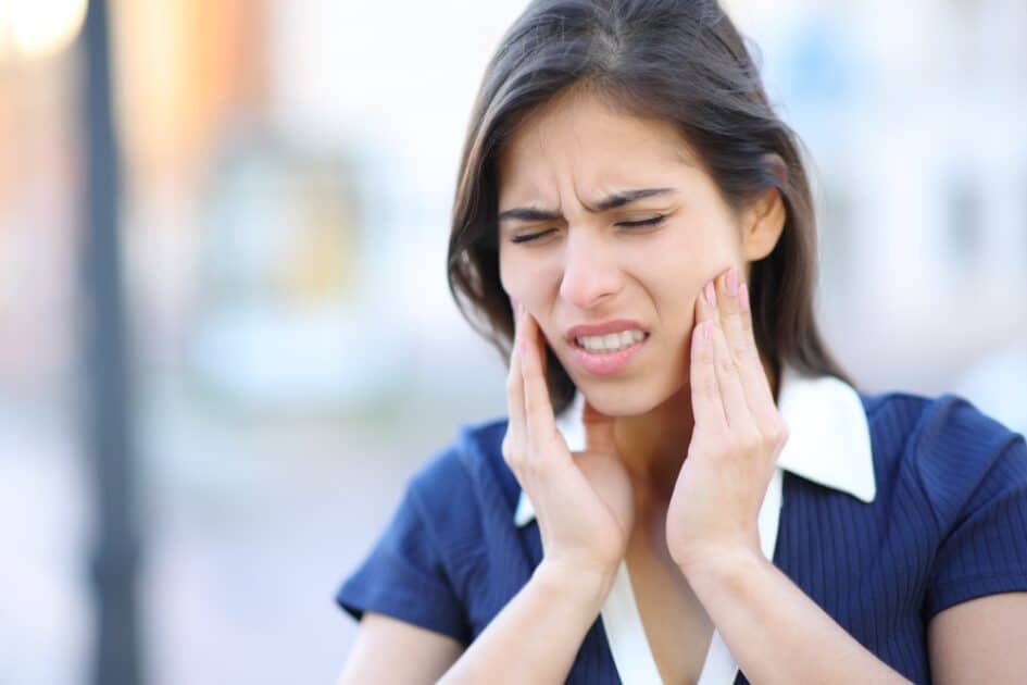 A stressed-out woman with tmj disorder complains on the street.