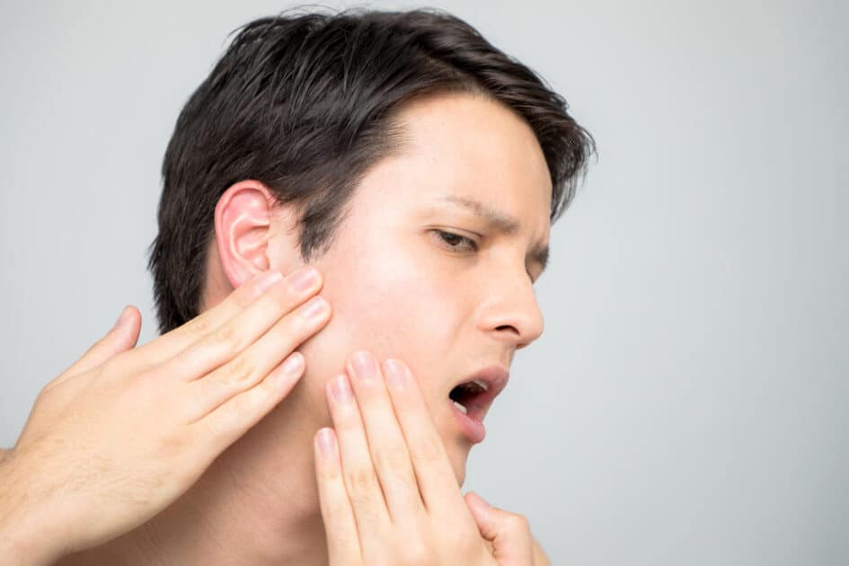 Man checking his jaw in the mirror