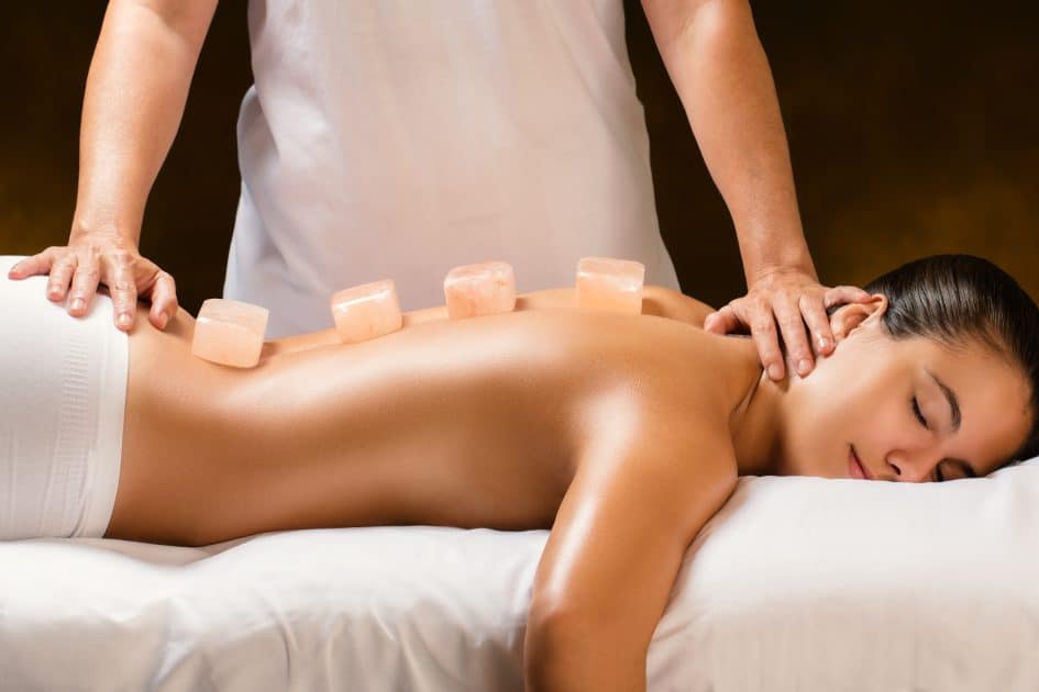 Therapist rubbing a woman's lower back with Himalayan Salt Stone Massage