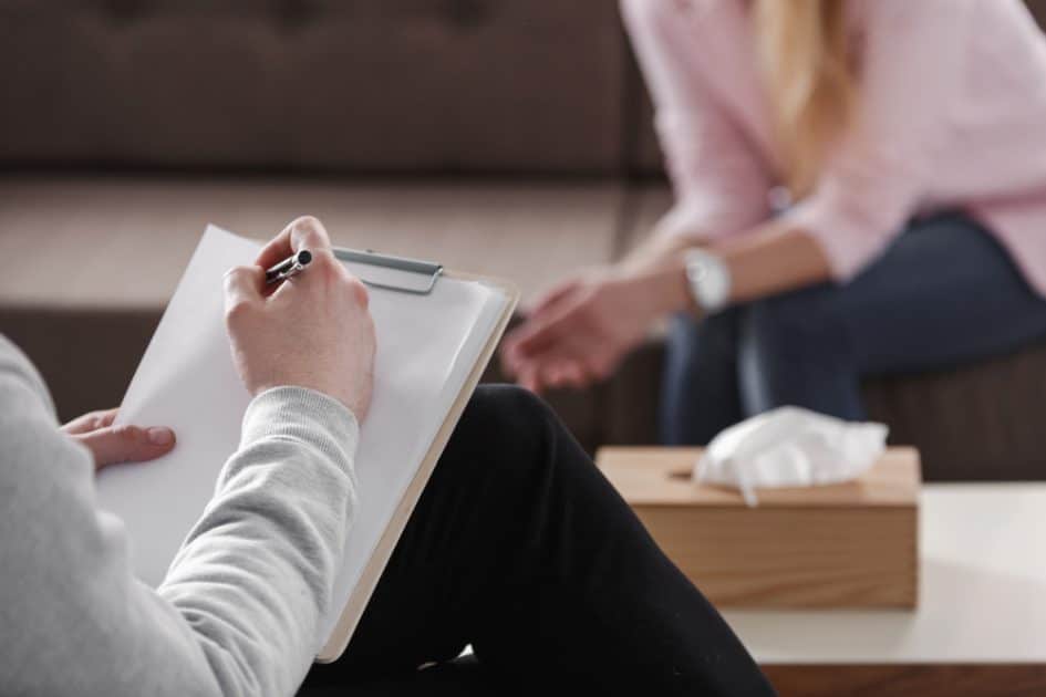 During a counseling session with a single lady, a therapist writes notes on her palm.