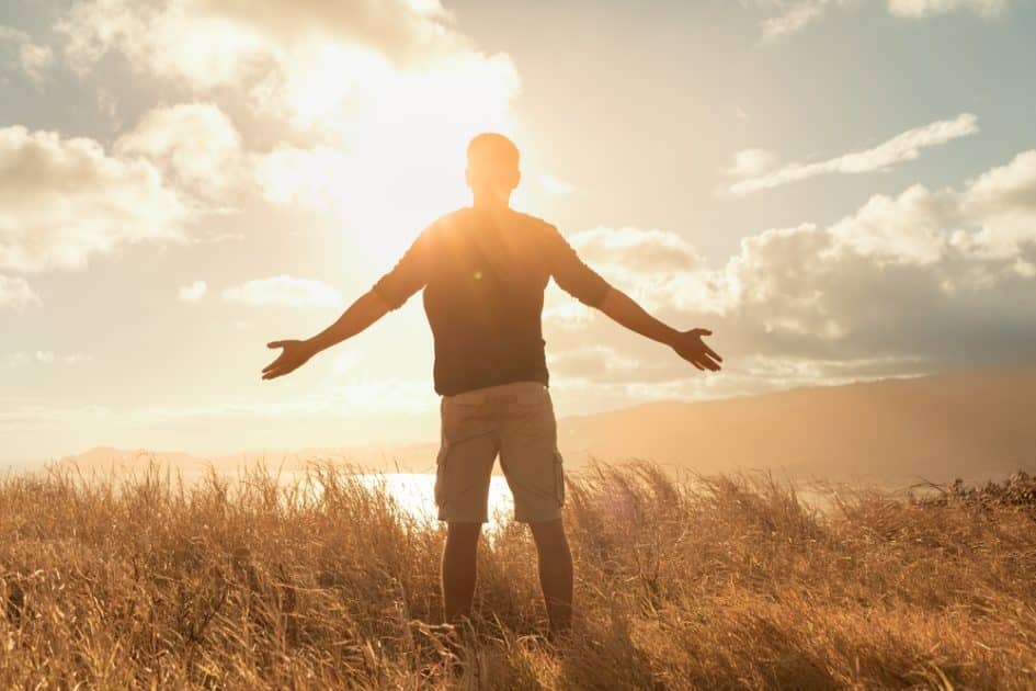 Man in grass watching sunset