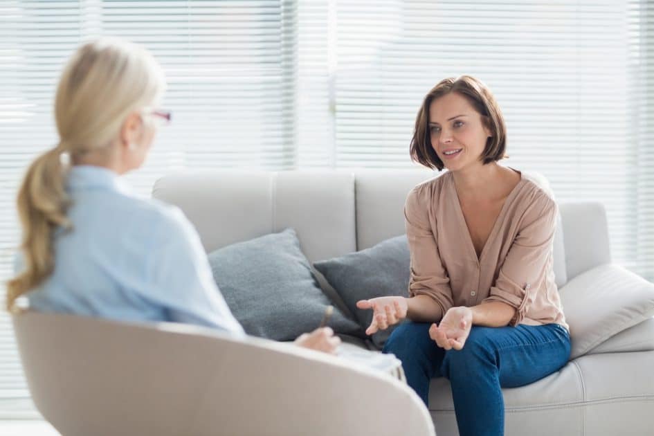 Woman on sofa at home conversing with therapist